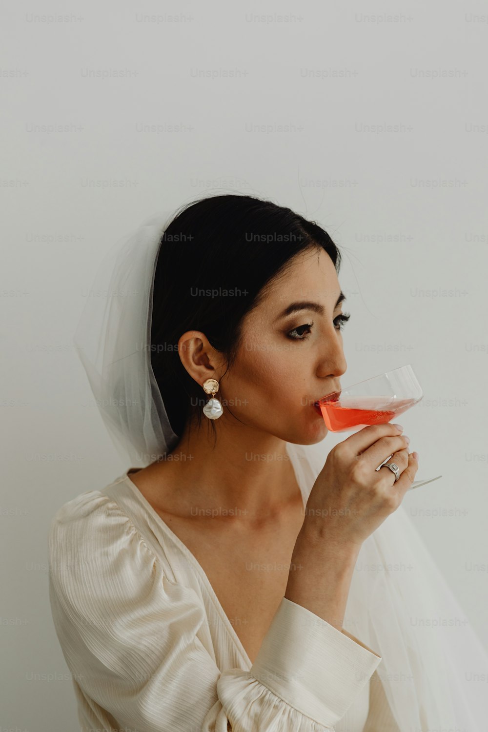 a woman in a wedding dress drinking from a wine glass