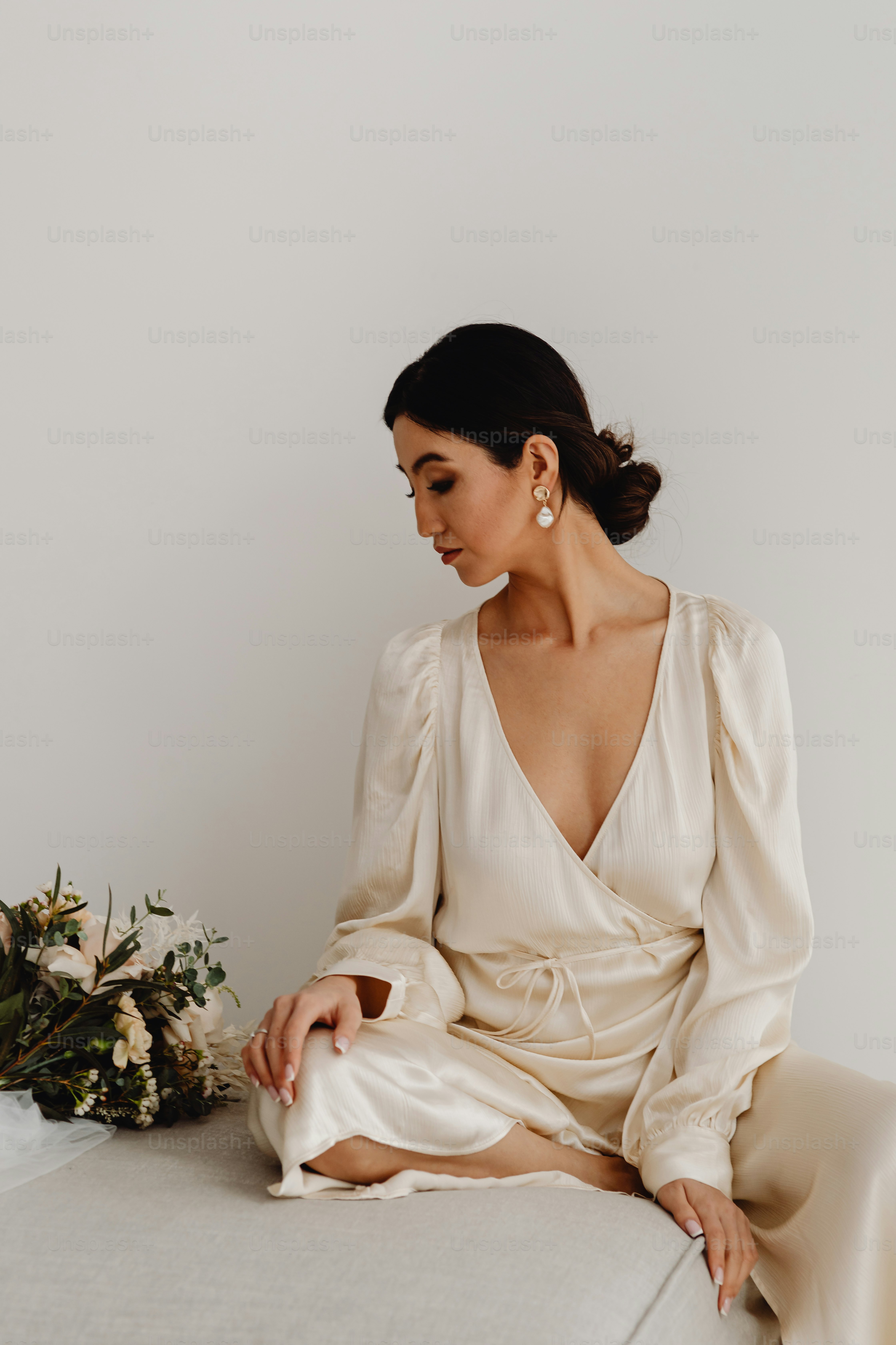 花束の隣のベッドの上に座っている女性