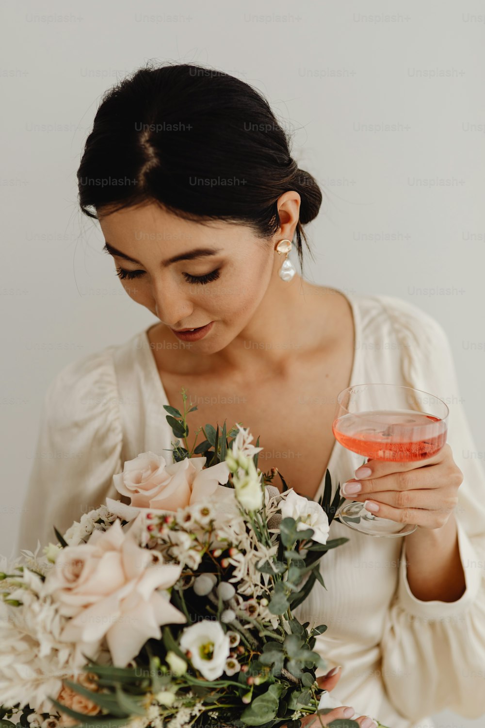 Eine Frau in einem weißen Kleid hält ein Glas Wein in der Hand