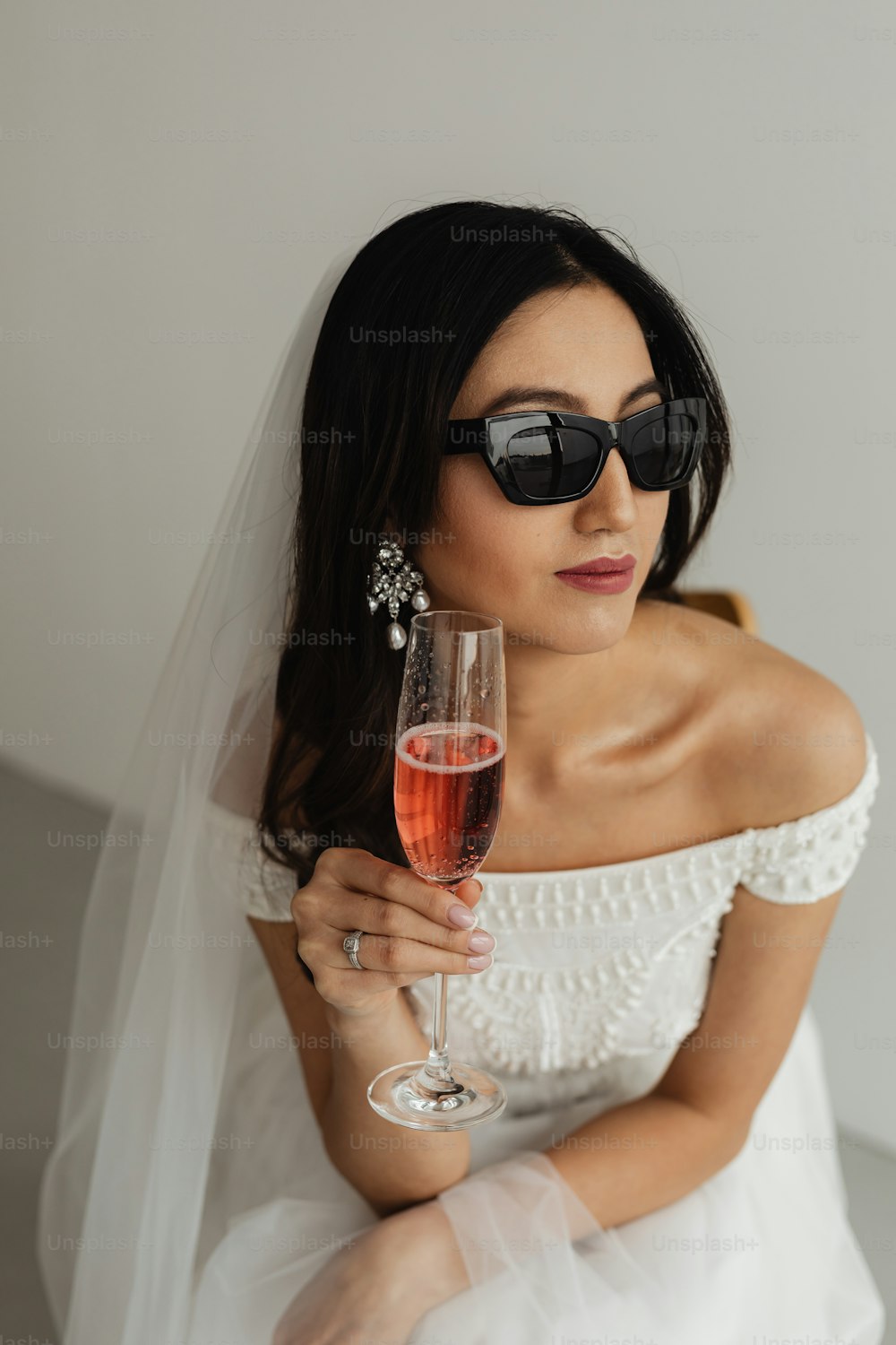uma mulher em um vestido de noiva segurando um copo de vinho