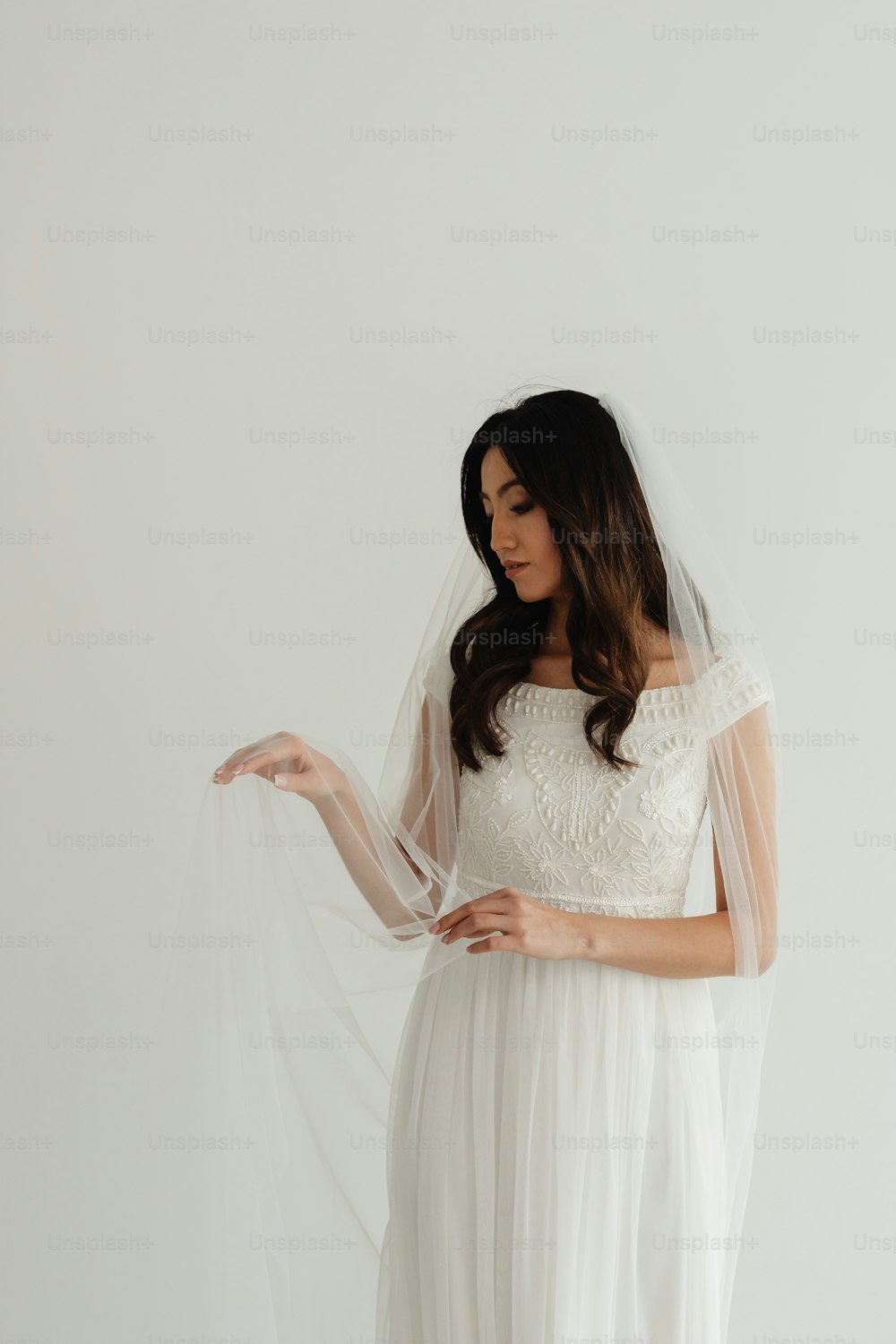 Una mujer con un vestido blanco sostiene un velo