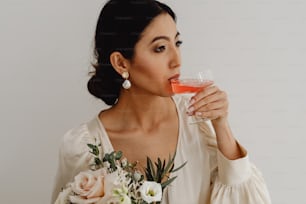 Une femme en robe blanche buvant un verre de vin