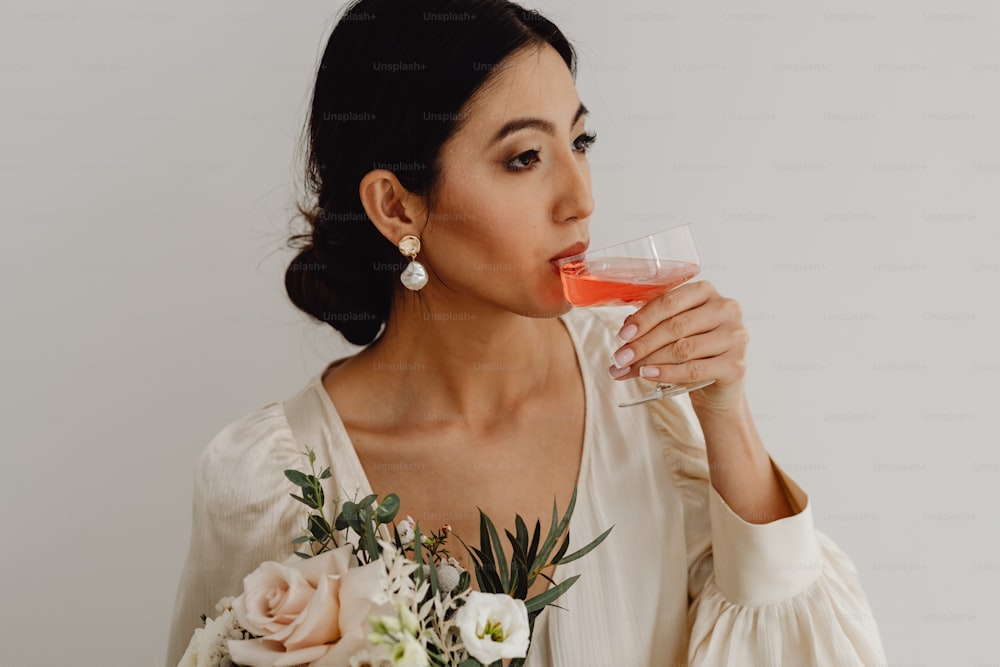 a woman in a white dress drinking a glass of wine