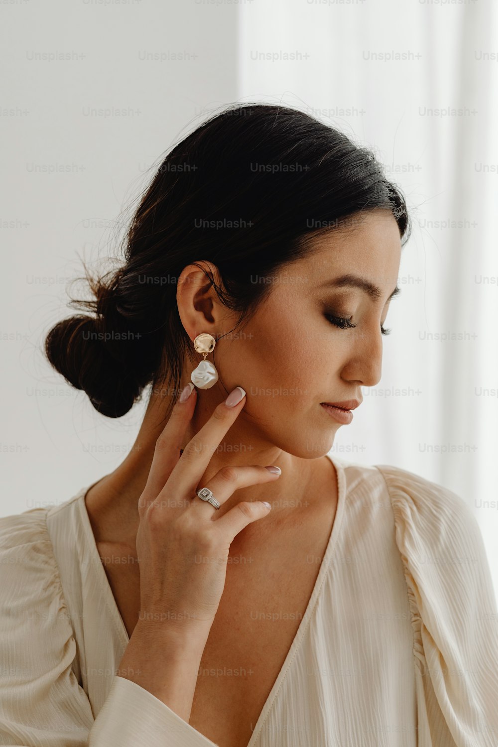 a woman wearing a white shirt and a pair of earrings