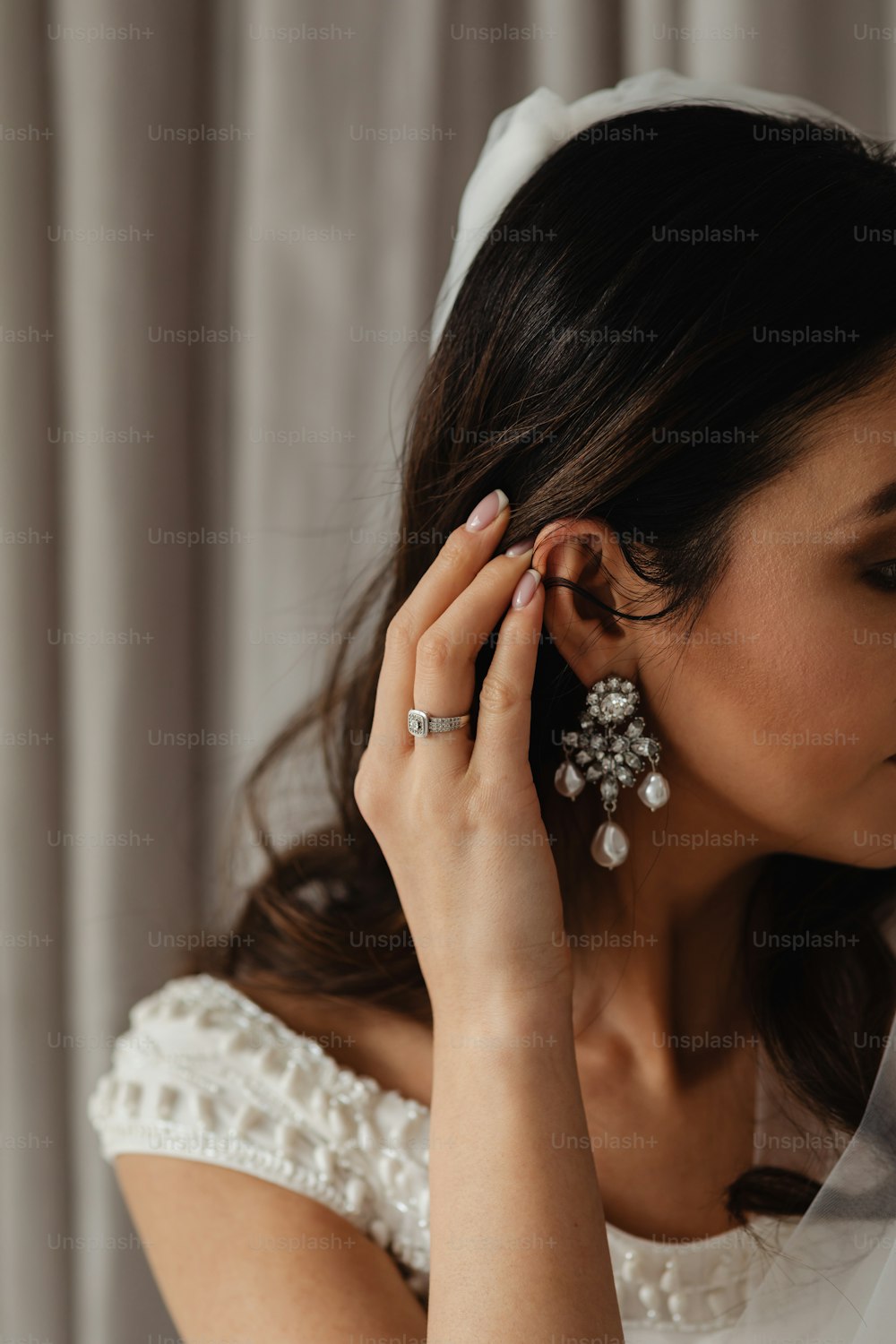 Eine Frau im Hochzeitskleid zieht ihre Ohrringe an