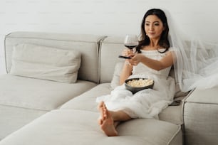 a woman sitting on a couch holding a glass of wine