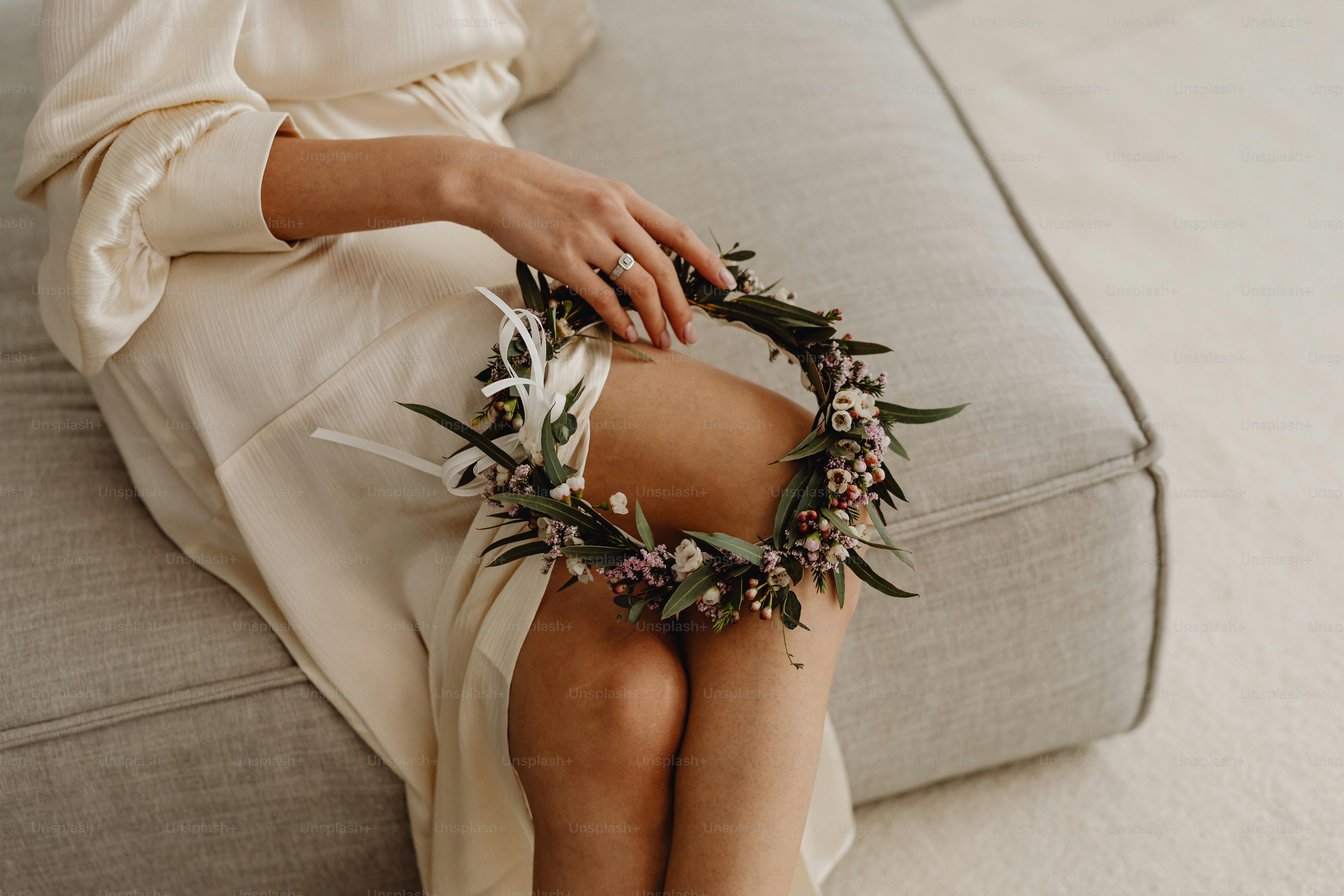 a woman sitting on a couch with a wreath around her ankles