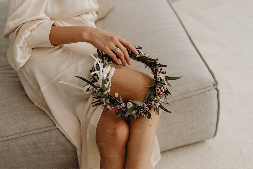 a woman sitting on a couch with a wreath around her ankles