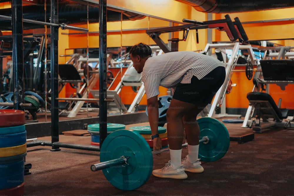 a man squatting down with a barbell in a gym