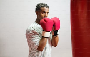 a man wearing boxing gloves standing next to a red punching bag