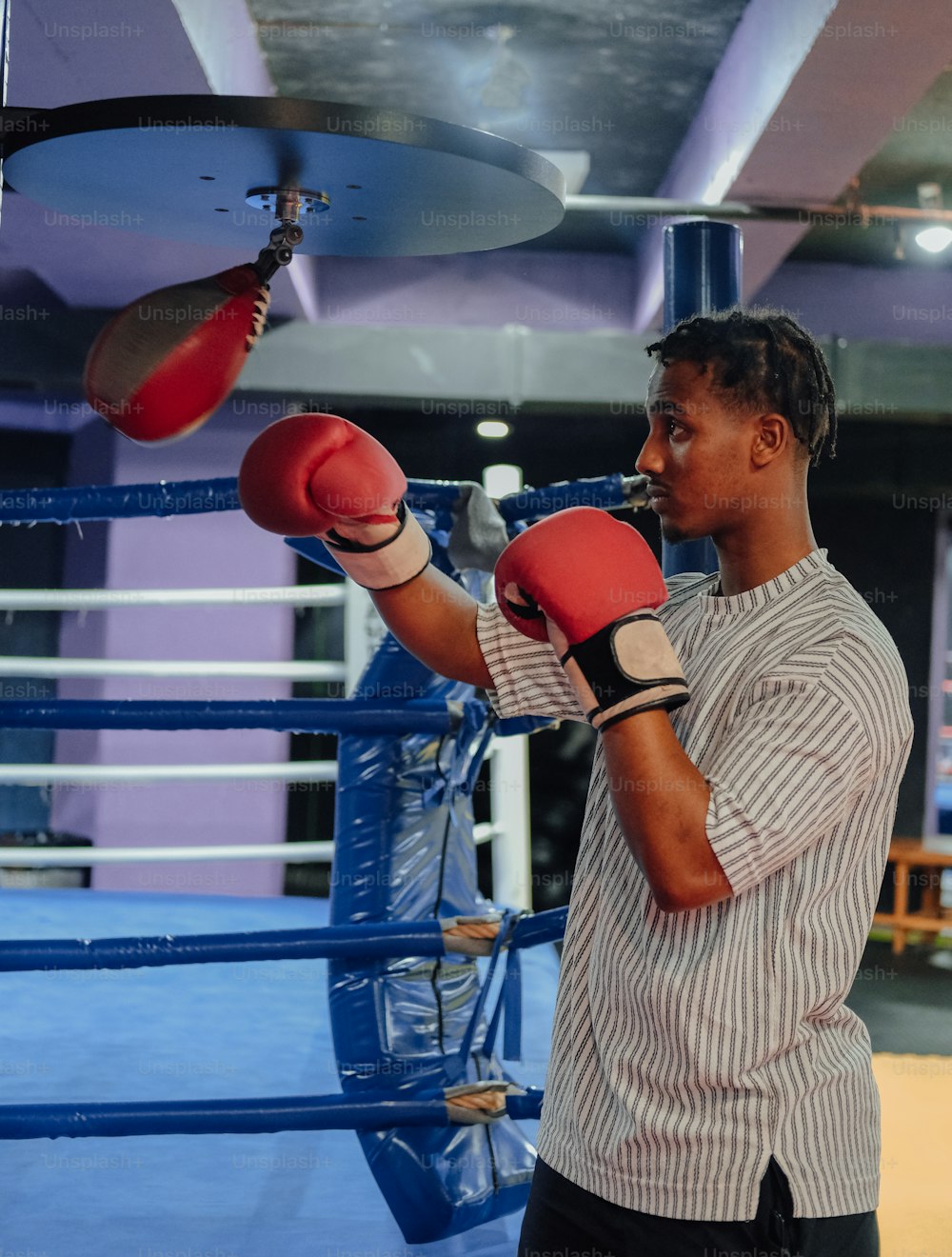 a man standing in a boxing ring wearing red boxing gloves