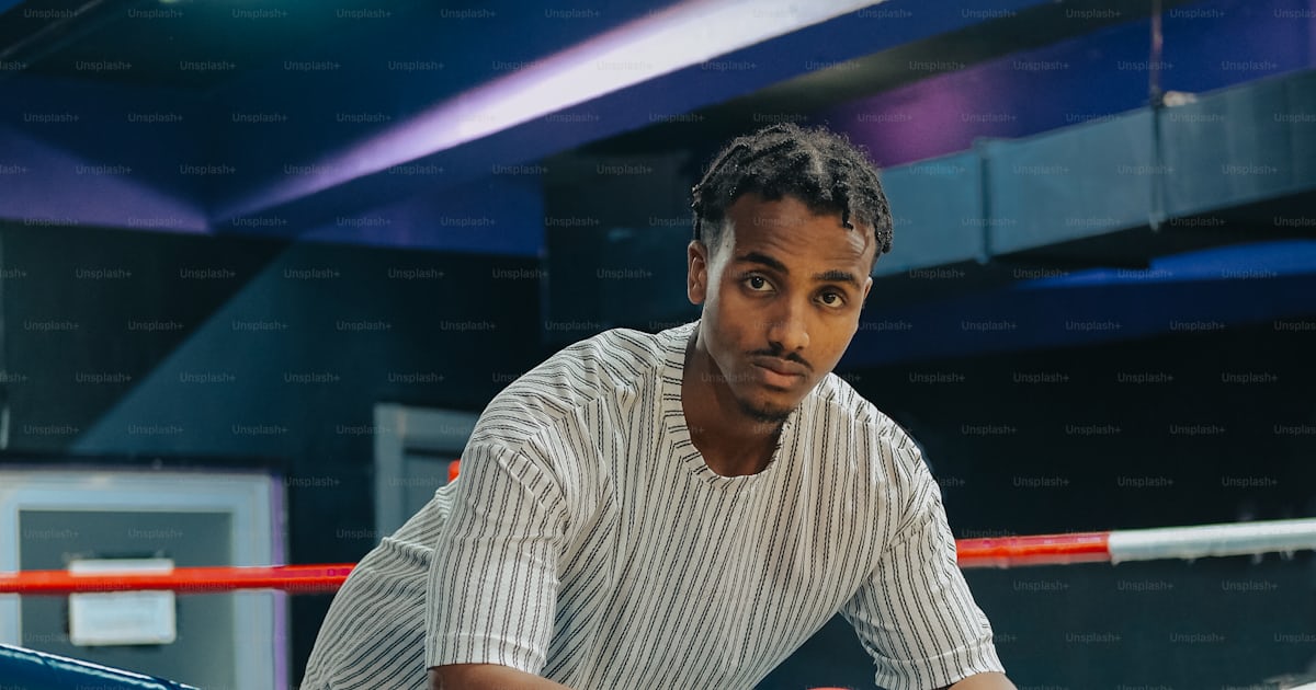 A man sitting in a boxing ring wearing red boxing gloves photo ...