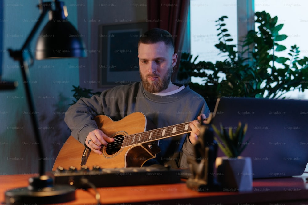 Un hombre sentado en un escritorio tocando una guitarra