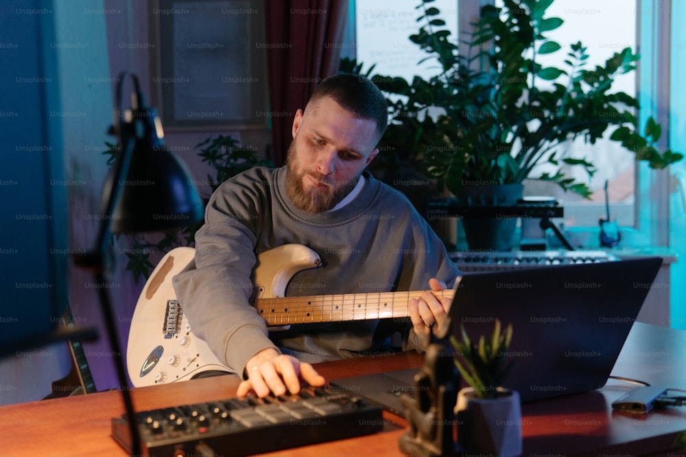 Un hombre sentado en un escritorio con una guitarra frente a él