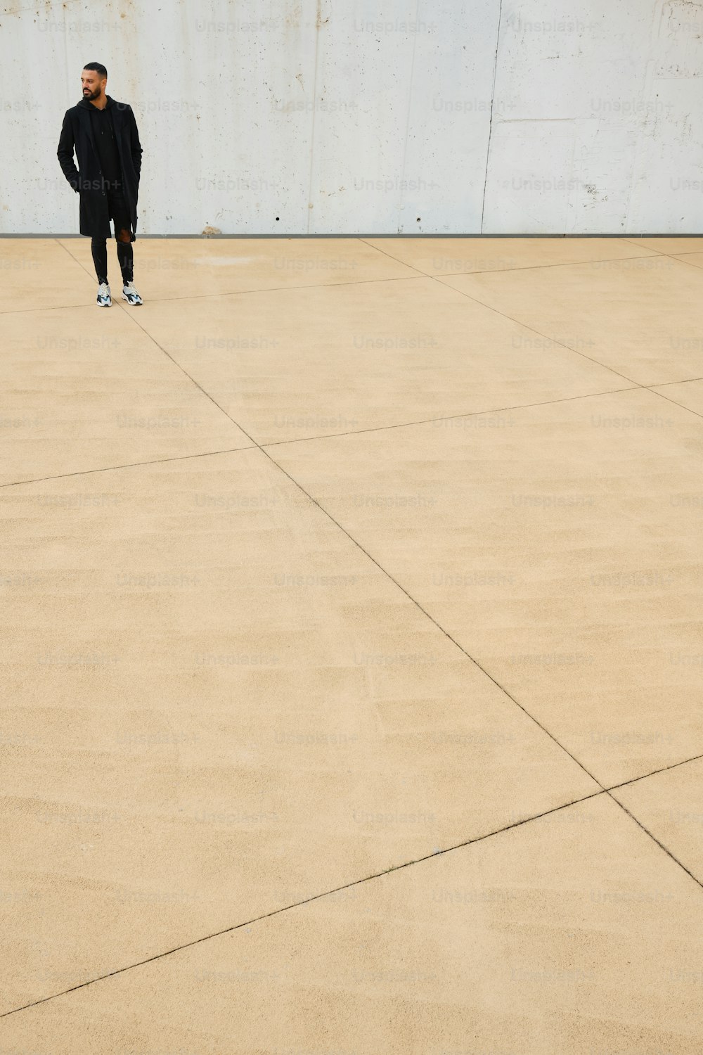 um homem em um terno preto de pé em um chão de concreto