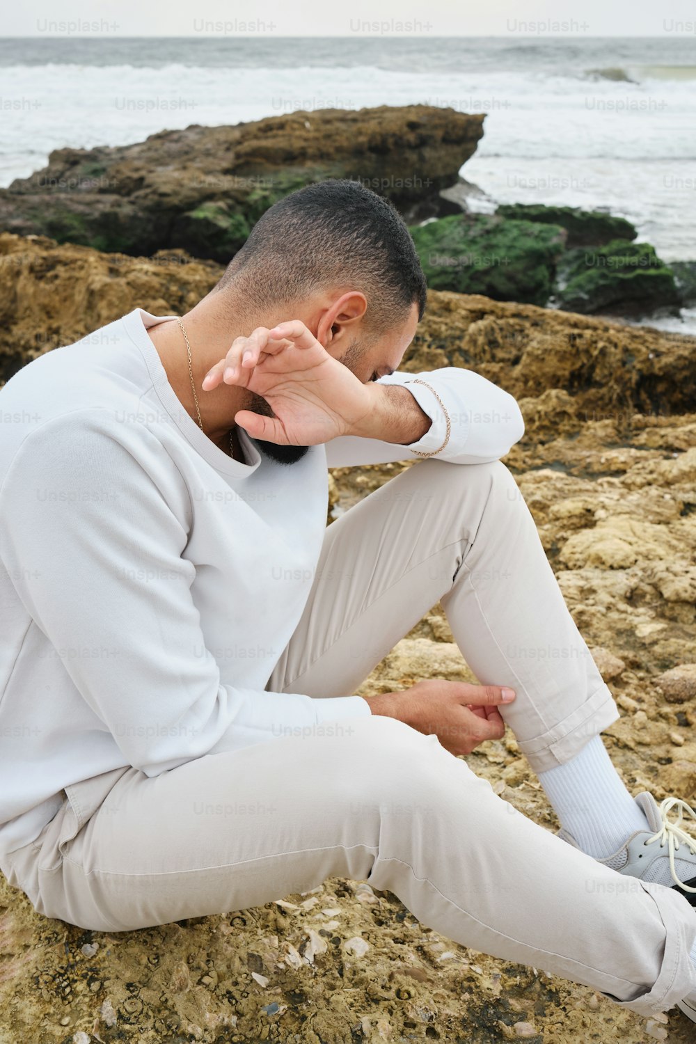 Un homme assis sur un rocher près de l’océan