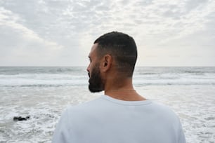 a man standing on a beach looking out at the ocean