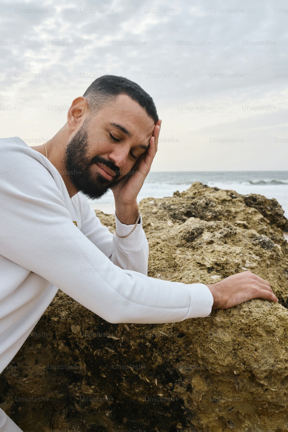 um homem sentado em uma rocha perto do oceano