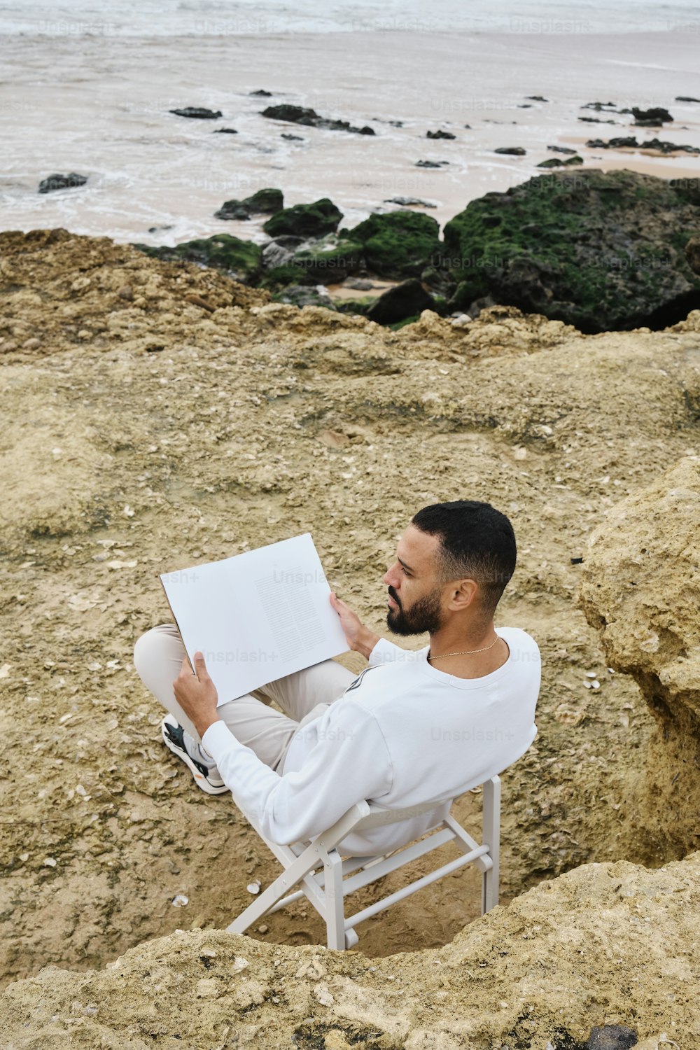 Un hombre sentado en una silla leyendo un libro