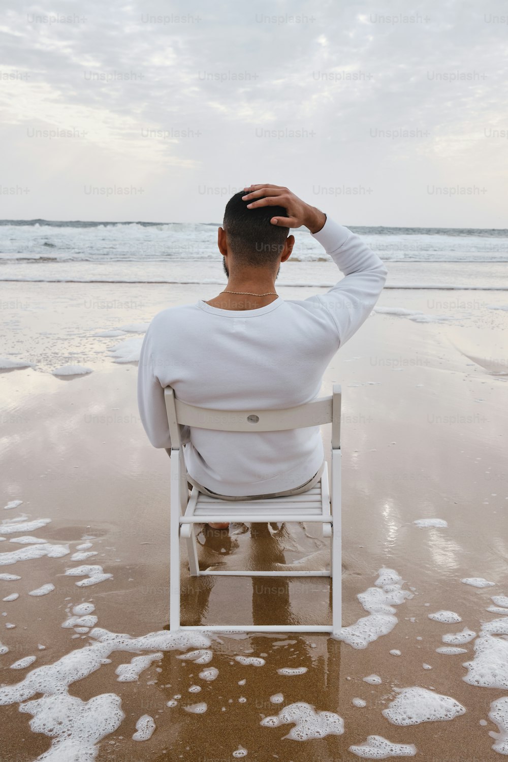 Ein Mann sitzt auf einem Stuhl am Strand