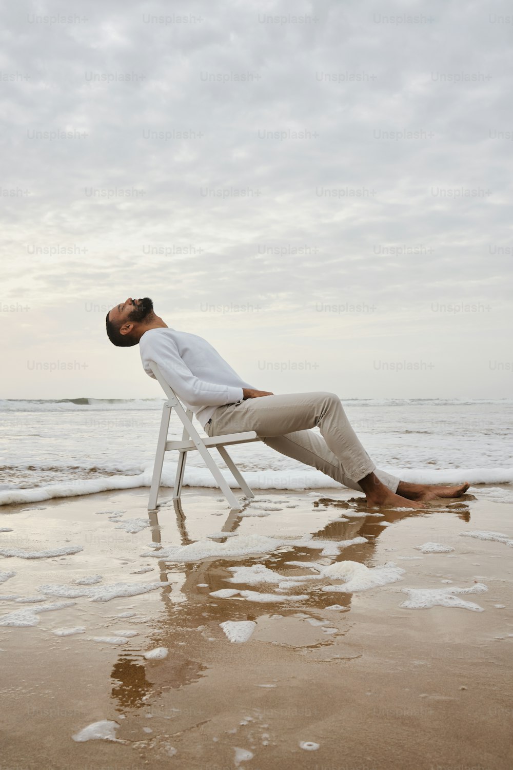 um homem sentado em uma cadeira na praia