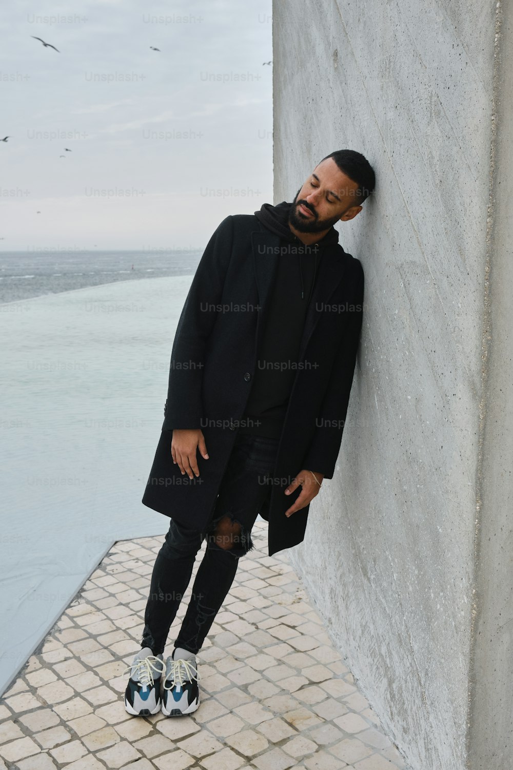 a man leaning against a wall with his foot on the ground