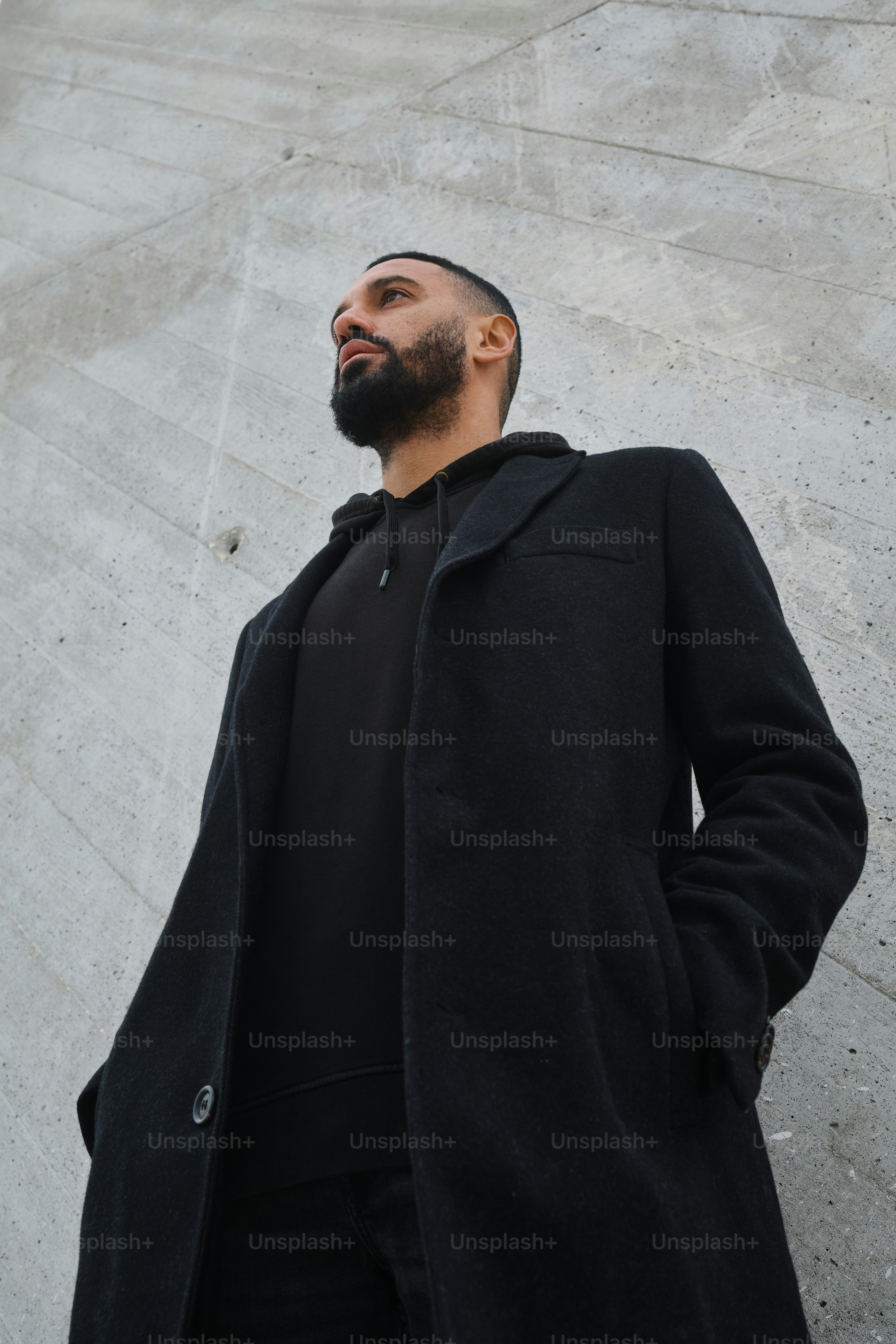 a man with a beard standing in front of a wall