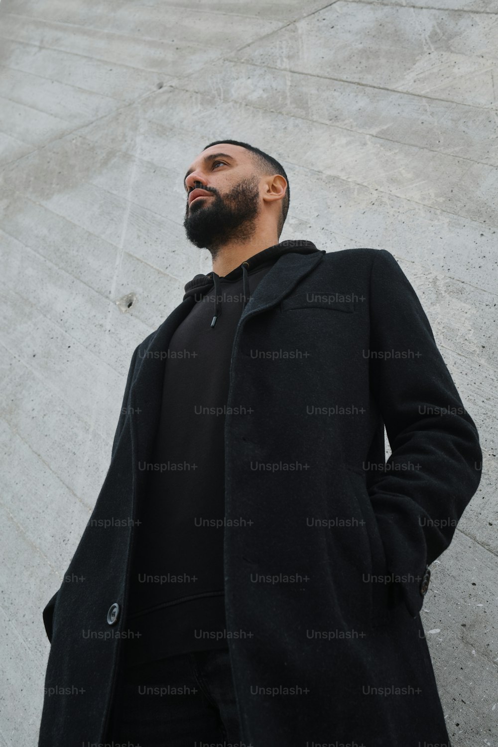 a man with a beard standing in front of a wall
