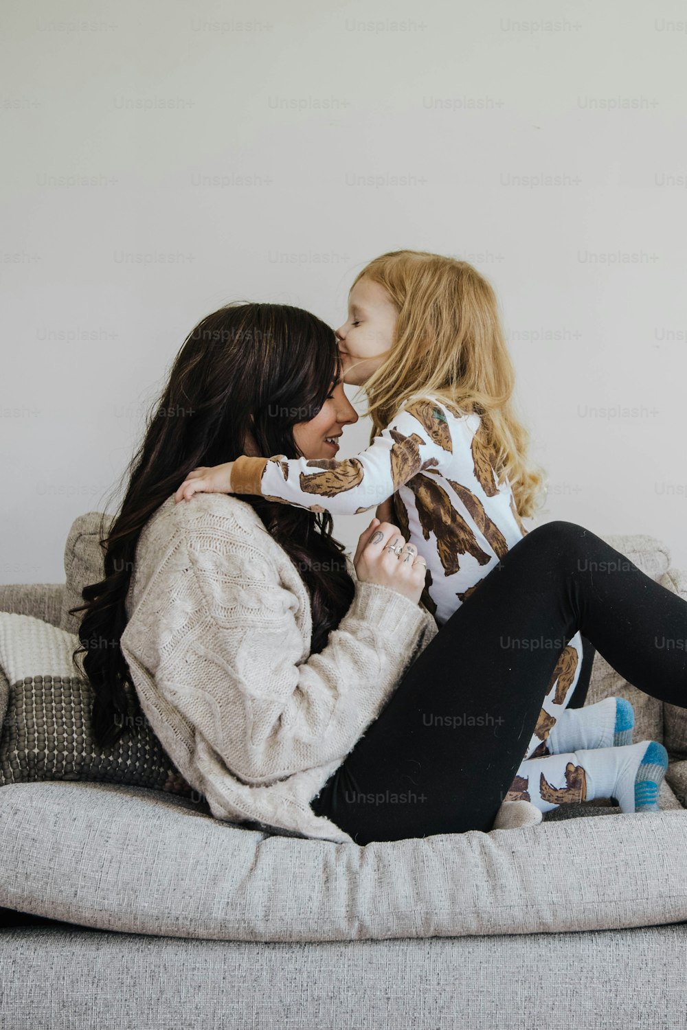 a woman sitting on top of a couch next to a little girl