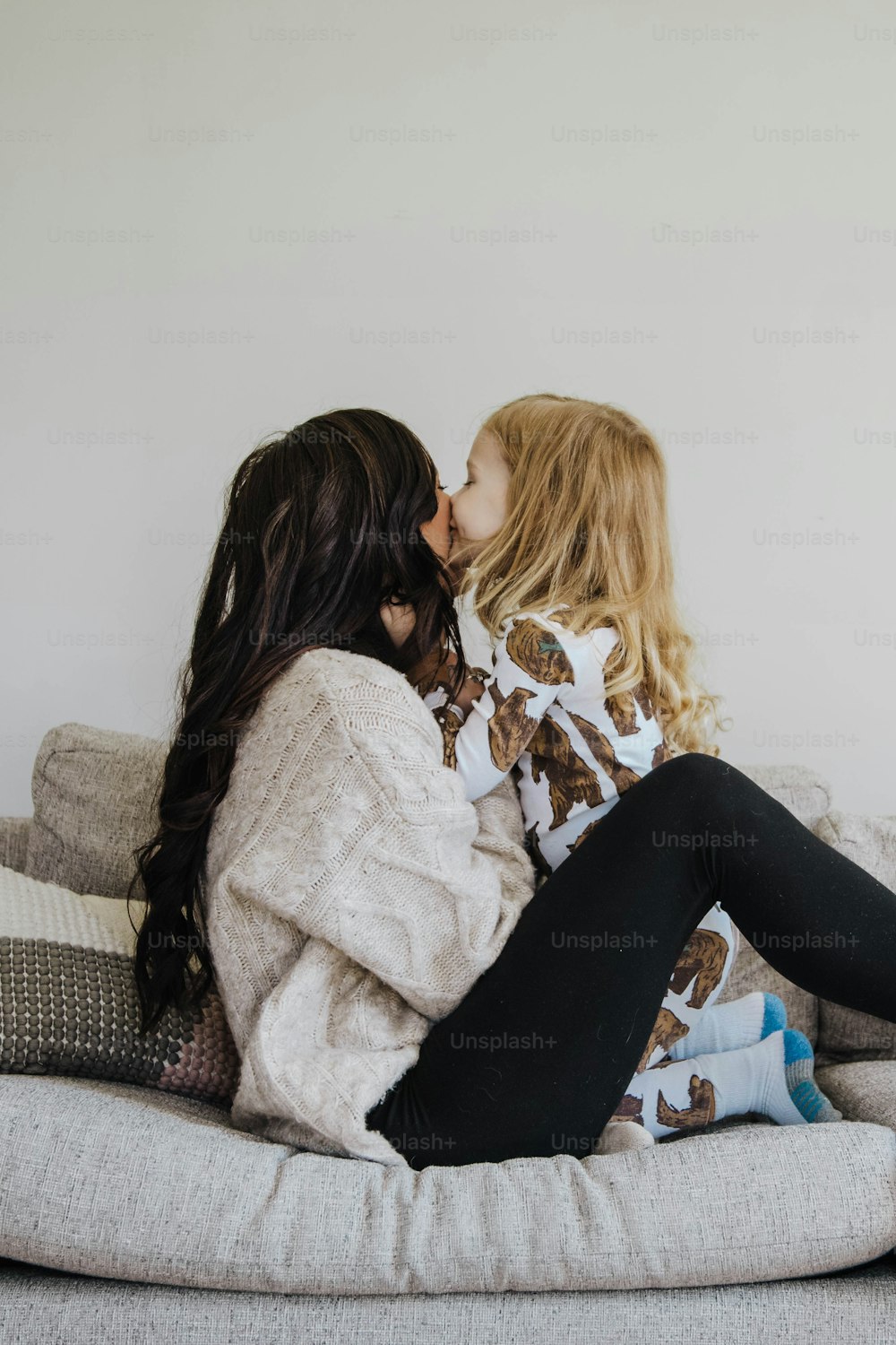 Due donne sedute su un divano che si baciano