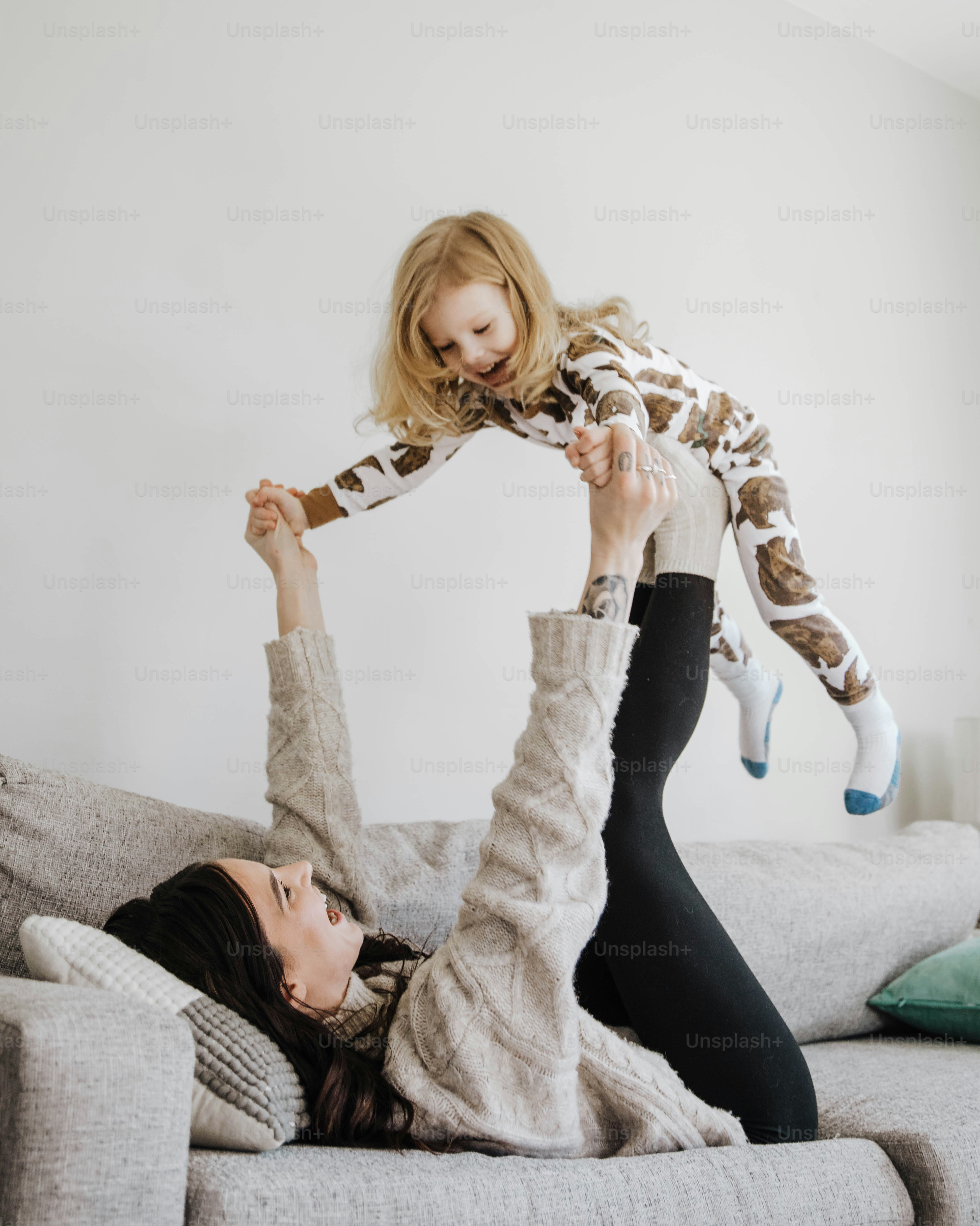 a woman laying on top of a couch holding a stuffed animal