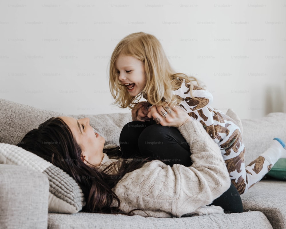 a woman holding a little girl on top of a couch