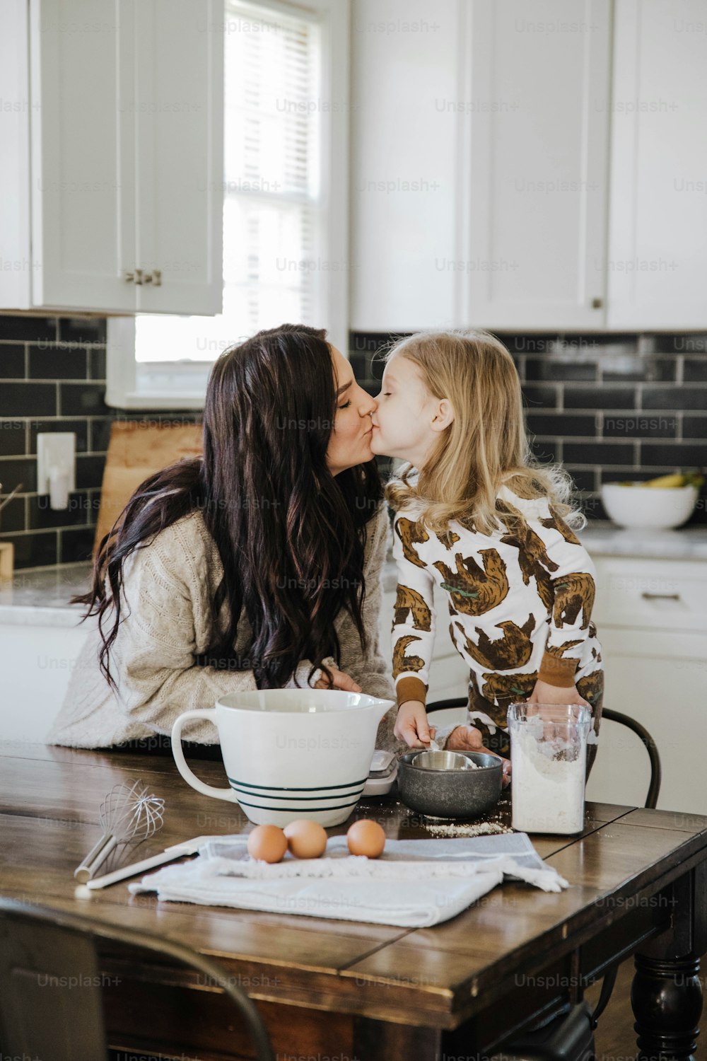 a mother kissing her daughter in the kitchen