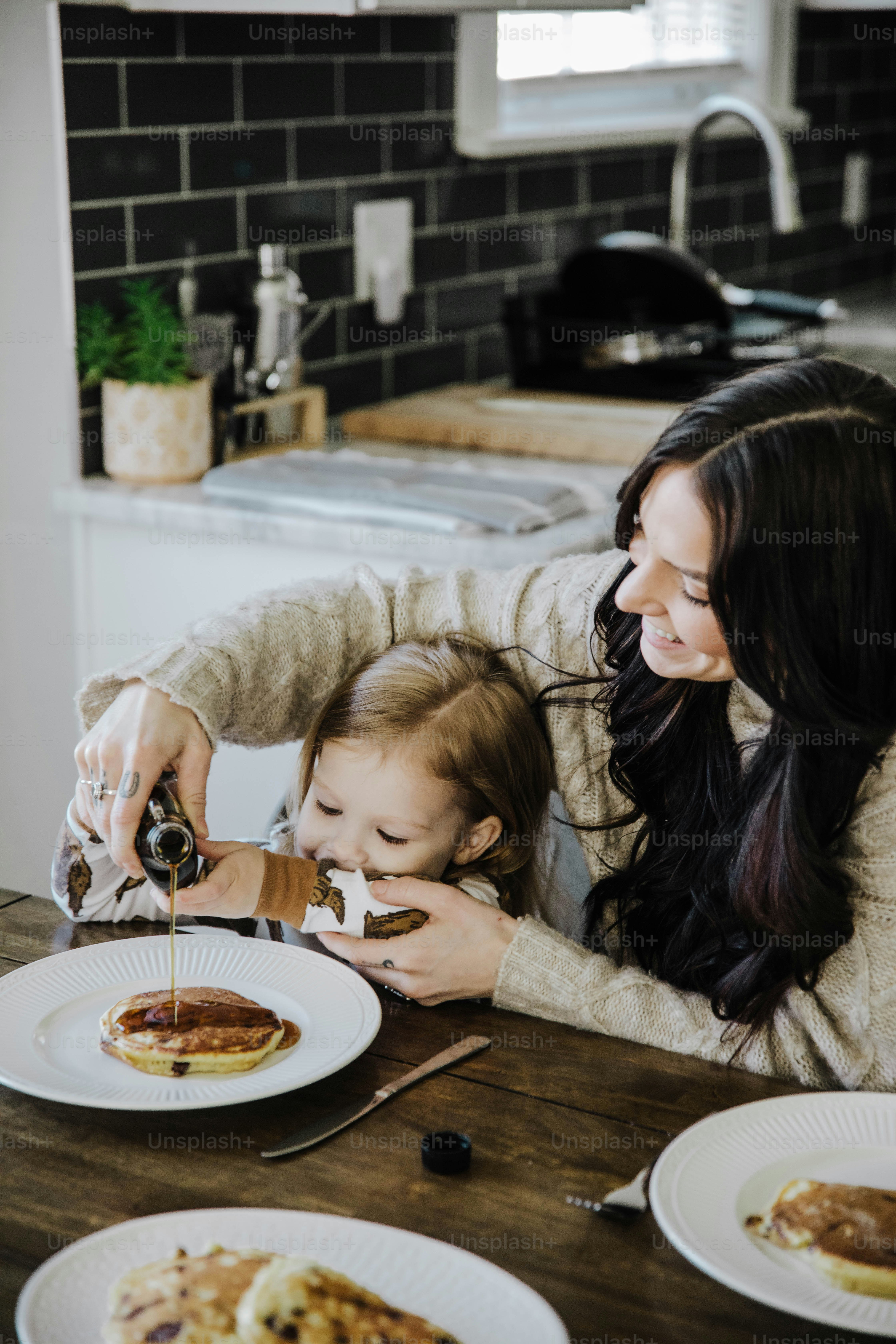 a woman and a child sitting at a table with plates of food