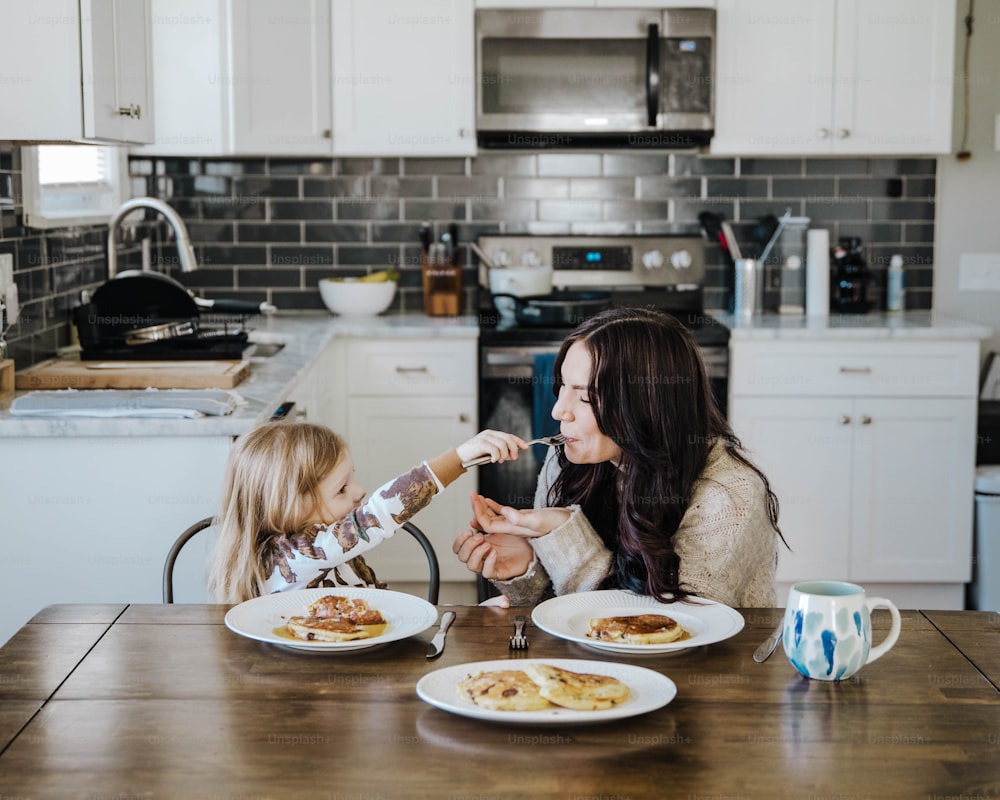 Eine Frau und ein kleines Mädchen sitzen an einem Küchentisch