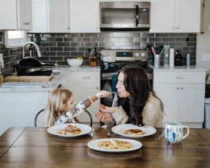 a woman and a little girl sitting at a kitchen table