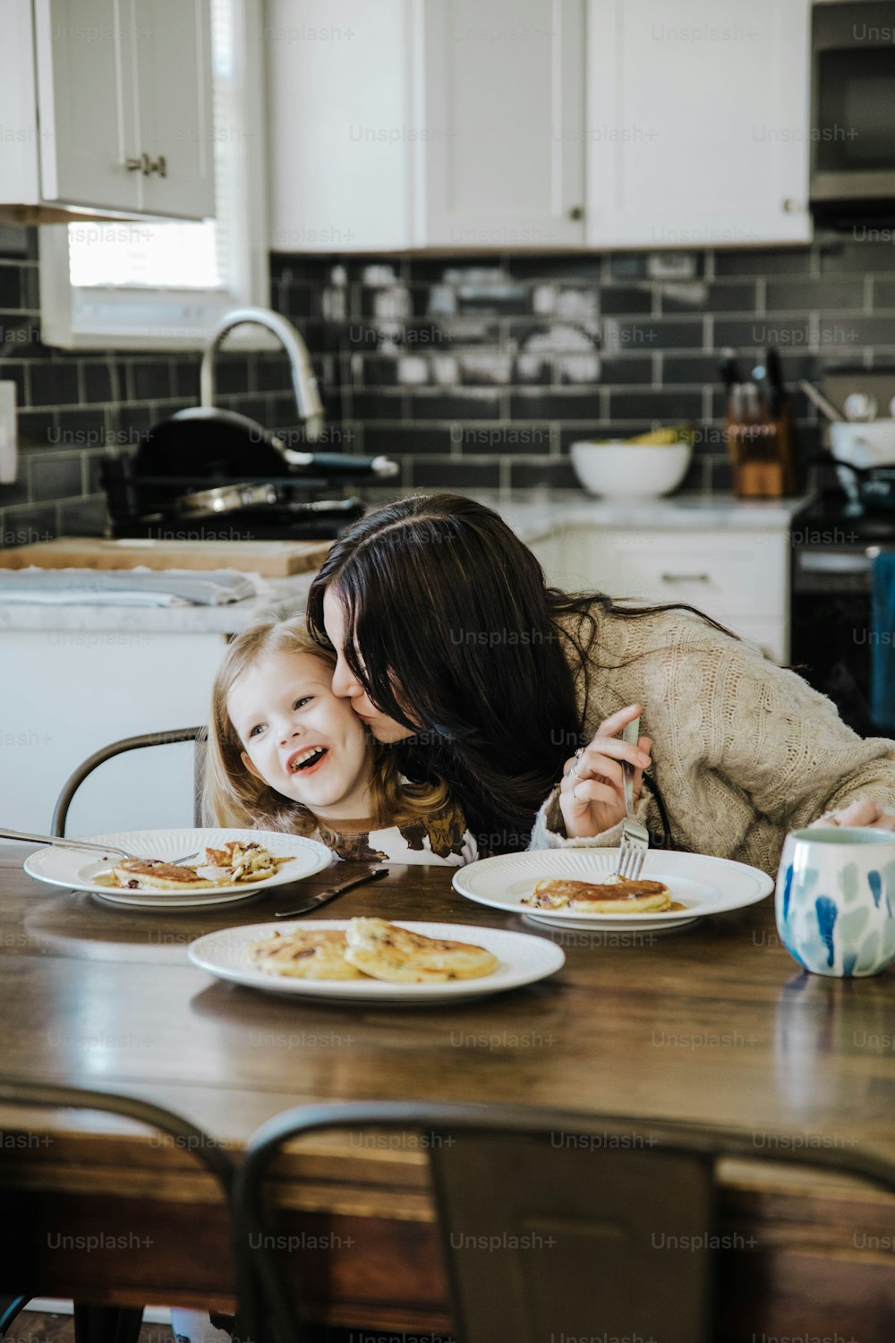 Eine Frau und ein kleines Mädchen sitzen an einem Tisch mit Tellern mit Essen