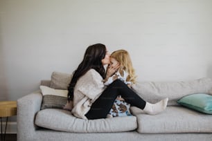 a mother kissing her daughter on the couch