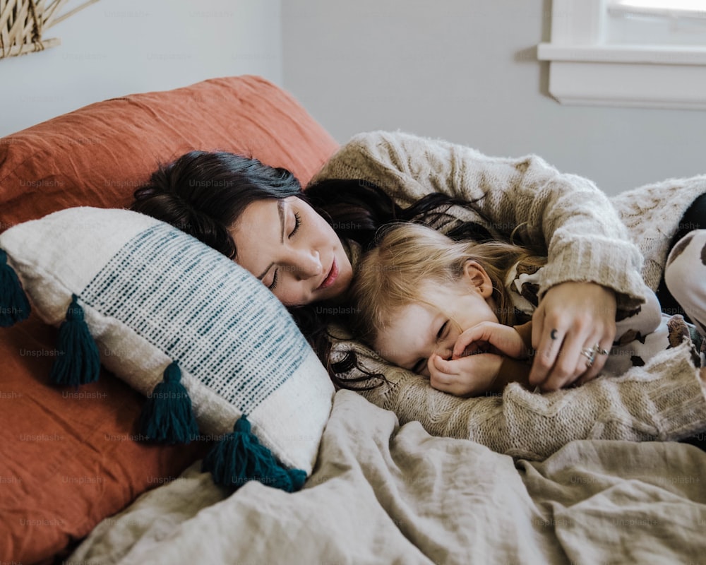 a woman and a child laying on a bed