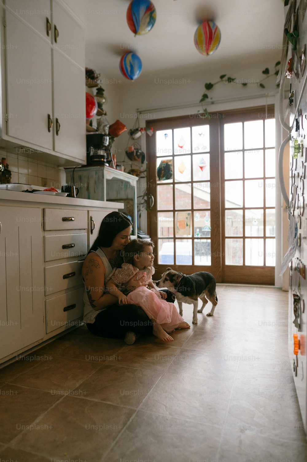 a woman sitting on the floor with a child and a dog