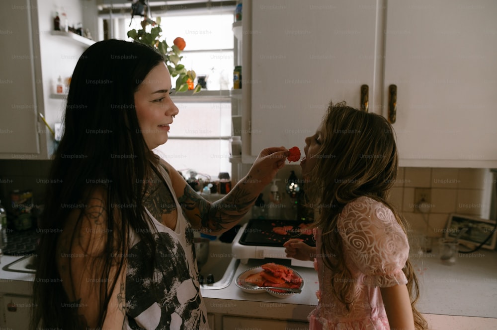 a woman and a little girl standing in a kitchen