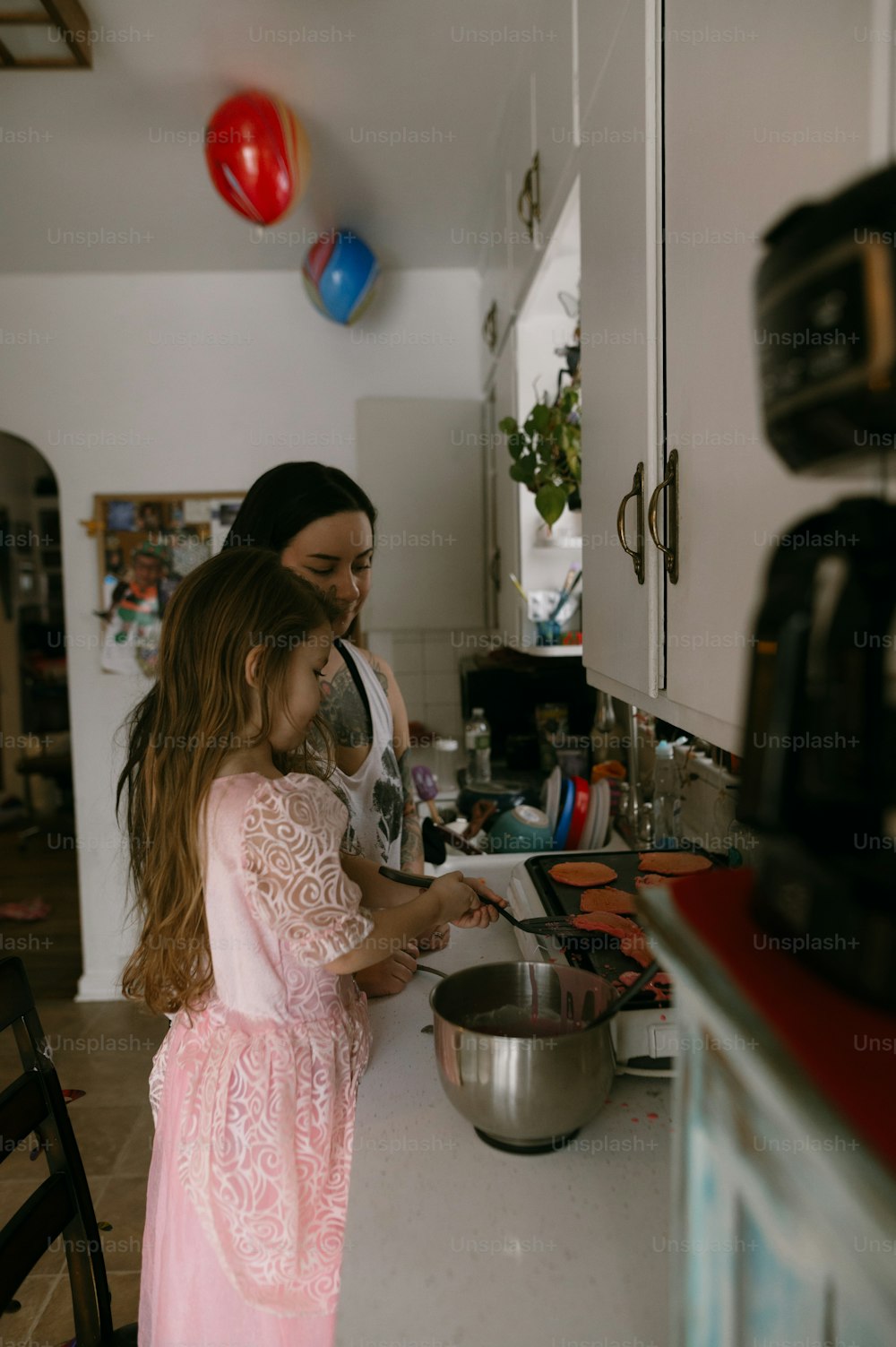 a woman and a little girl cooking in a kitchen