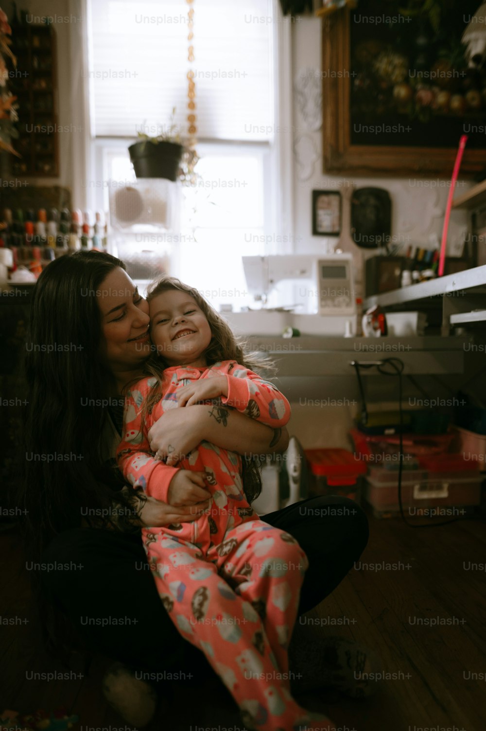 uma mulher que abraça uma menina pequena em uma cozinha