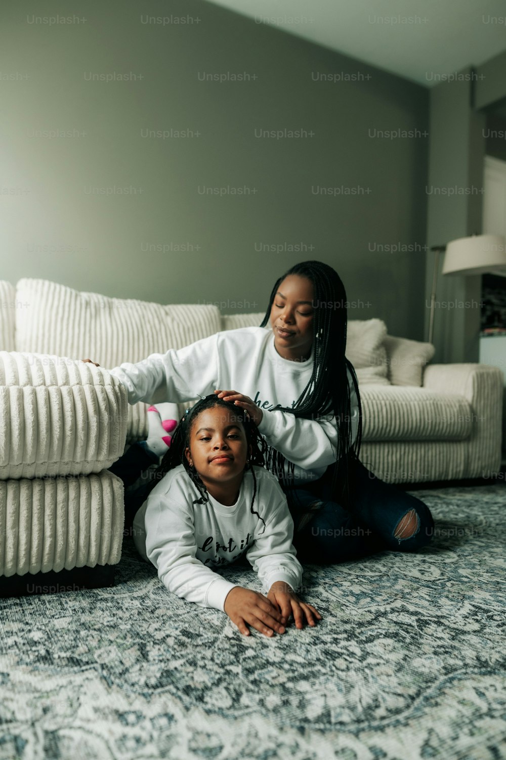 a woman sitting on the floor next to a little girl