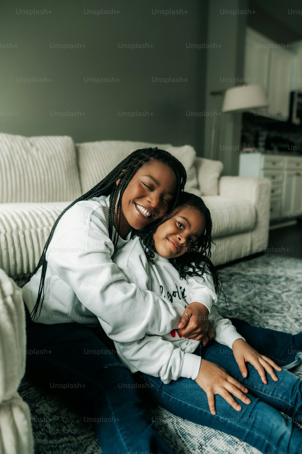 a mother and daughter sitting on the floor in a living room