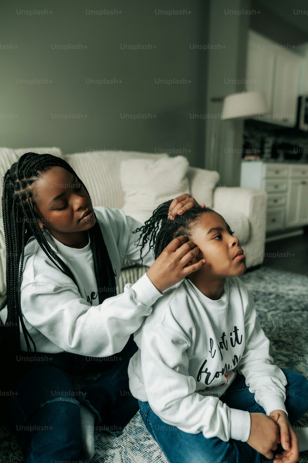 a woman combing a child's hair while sitting on the floor