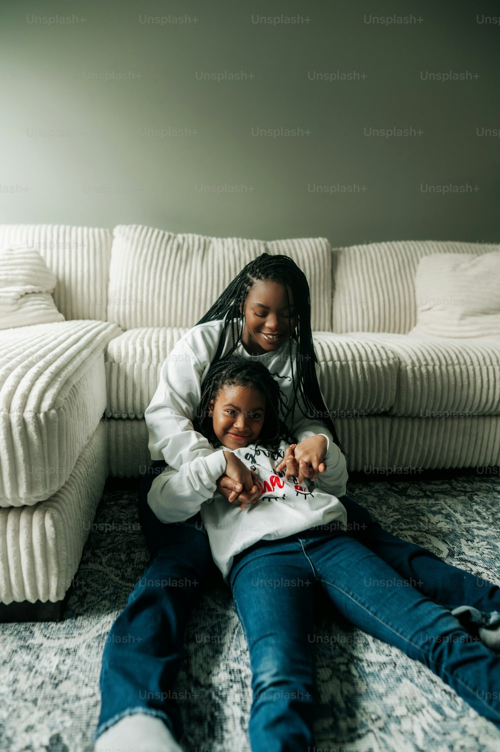 two girls sitting on the floor in front of a couch