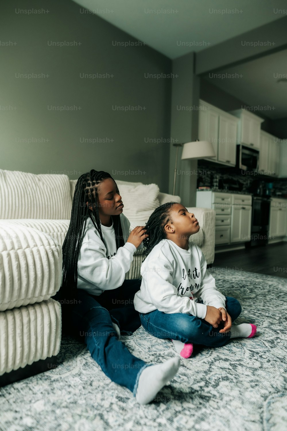 Deux jeunes filles assises sur le sol d’un salon