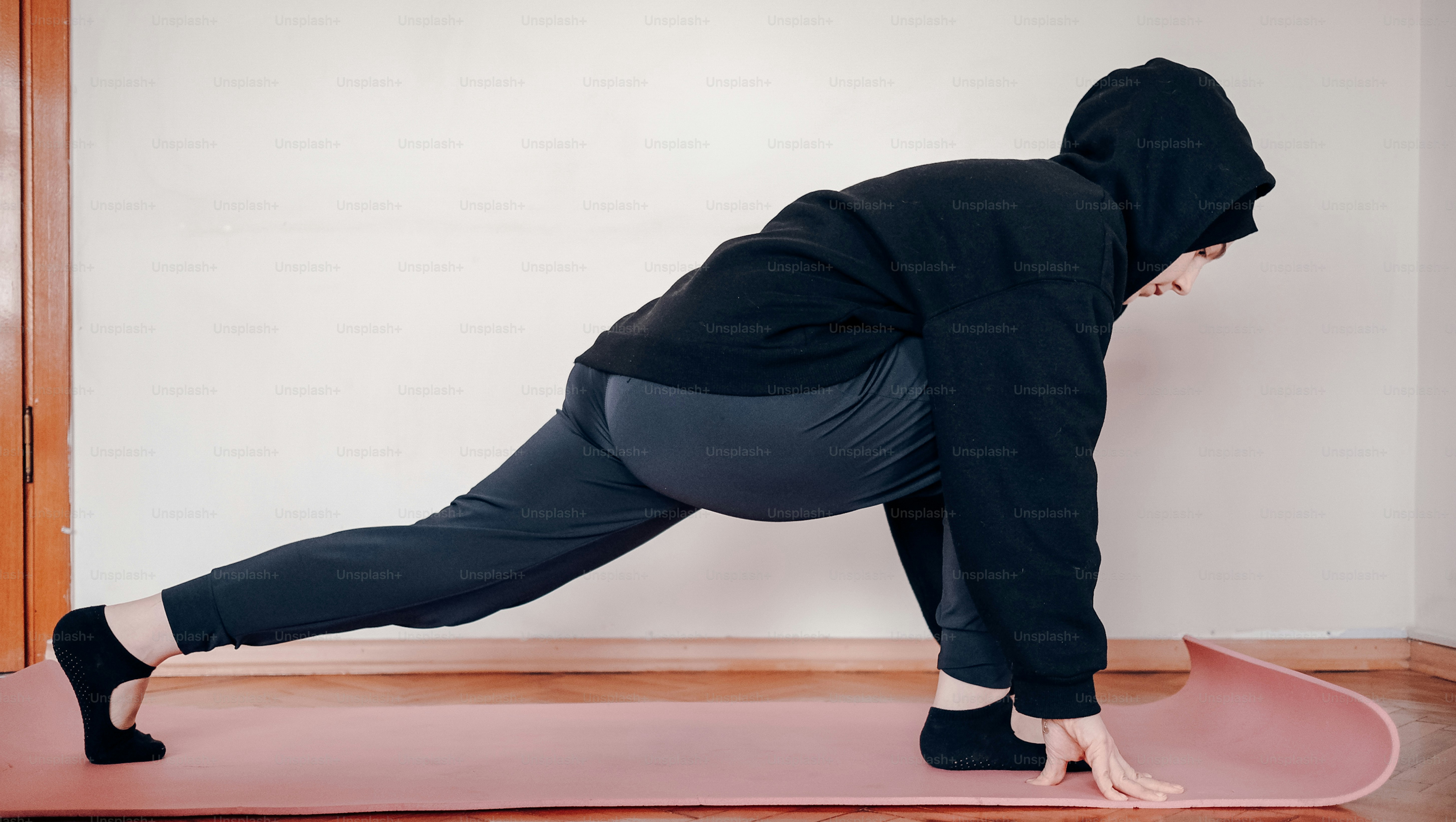 a person in a black hoodie is doing a yoga pose