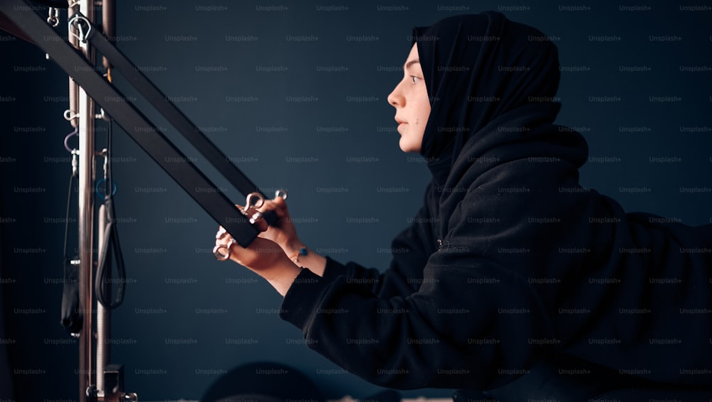 a woman in a hijab is working on a machine